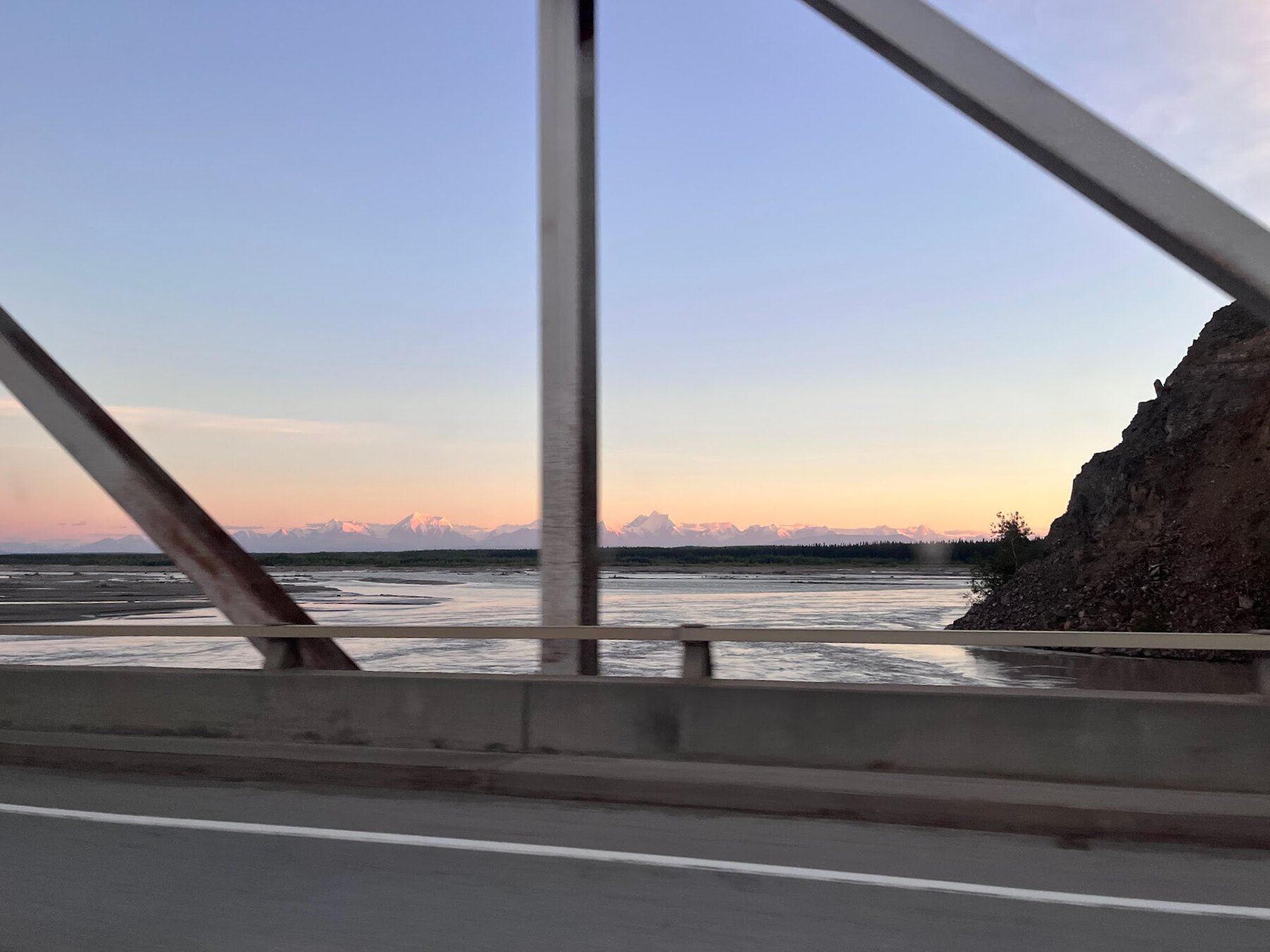 Bridge structure over an Alaska river with mountains in the distance